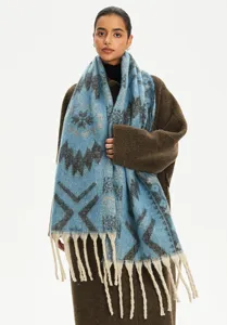 Detail view of a soft blue jacquard scarf with ethnic patterns and tassels.
