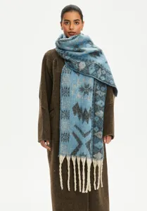 Long blue ethnic jacquard faux mohair scarf with white tassels worn over a brown coat.
