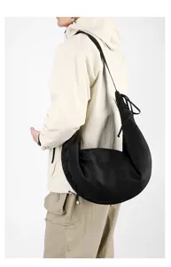 Detailed view of a large black nylon crescent crossbody bag worn over the shoulder.