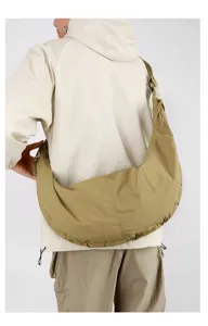 Large khaki nylon crescent hobo bag worn by a model in a minimalist studio setting