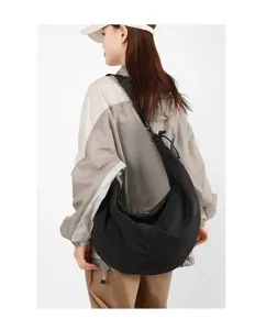 Large capacity black nylon crescent hobo bag worn by a model for a casual commuting style