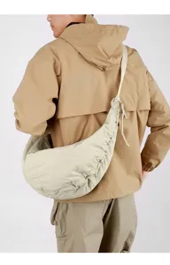 Detailed view of a stylish beige nylon crescent crossbody bag with pleated design on model.