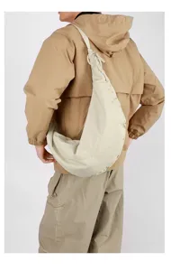Detailed back view of a person wearing a large cream nylon crescent hobo sling bag.