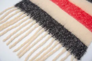 Dettaglio ravvicinato di una morbida sciarpa a righe in finto mohair con nappe e trama.
