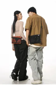 Back perspective of models wearing the functional mesh messenger bags in black and orange