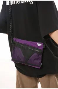 Close-up showing the purple and black nylon sacoche bag worn on a model in a street style look