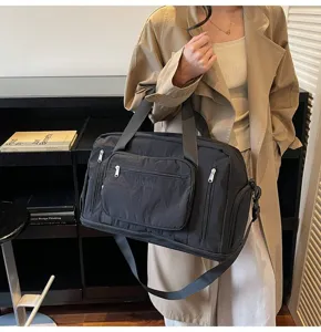 Professional view of a black large-capacity travel bag carried by a model in a beige coat