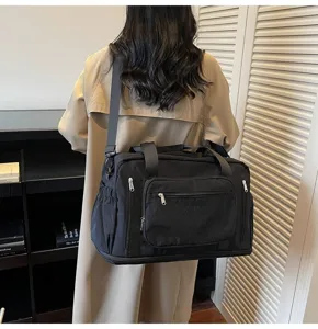 High-capacity black nylon travel duffel bag shown on shoulder in a lifestyle setting