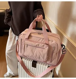 A detailed view of a pink large capacity travel duffel bag on top of a white suitcase