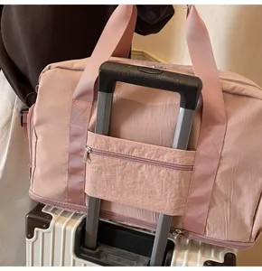 Close-up view of a pink expandable travel bag with a sleeve over a suitcase handle