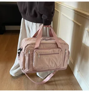 Detailed view of a large pink multi-pocket travel bag being held by a person in an indoor setting