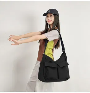 Detailed view showing the large capacity black vintage canvas messenger bag worn by a model