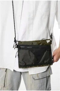 Detailed view of an olive green Japanese workwear crossbody bag worn with a white shirt