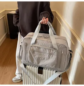 Large capacity grey nylon travel bag resting on a white suitcase for easy transport