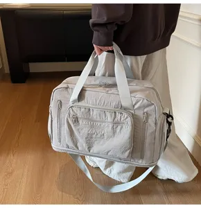 Large capacity gray travel bag shown in a lifestyle indoor setting with a person.