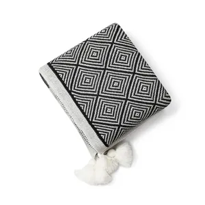 Folded black and white geometric knitted throw blanket with white tassels
