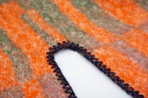 Close-up of black blanket stitch edging on a thick orange striped faux mohair shawl