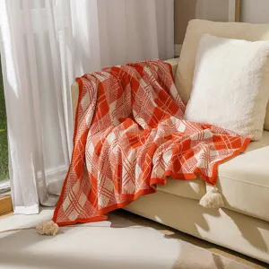 Detailed view of bohemian orange and white plaid knitted throw blanket with tassels
