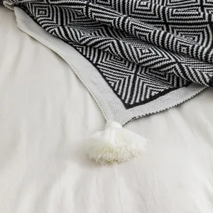 Close-up of Bohemian knit blanket with black white geometric pattern and white tassel