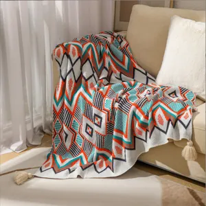 Cozy Bohemian geometric knitted throw blanket with elegant tassels on a beige sofa