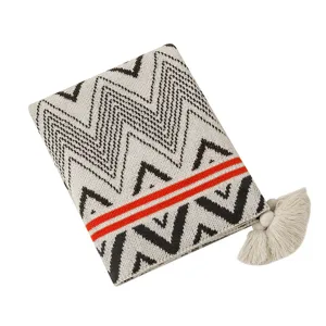 Close-up of bohemian knitted blanket with zigzag patterns and decorative tassel ball.