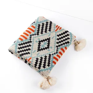 Detail of folded bohemian knitted blanket with geometric pattern and cream tassels
