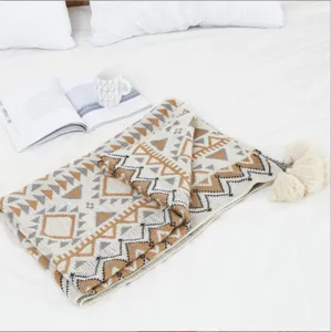 Close-up detail of a bohemian style knitted throw blanket with ethnic patterns and tassels