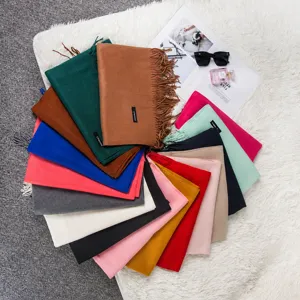 Close-up showing various colorful solid scarves with stylish tassels in a fanned layout.