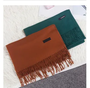 Detail of folded solid color scarves with tassels on a soft white shaggy background.