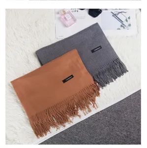 Close-up showing the soft texture of camel and grey solid color scarves with fringe tassels