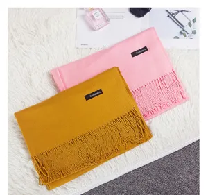 Close-up of pink and mustard yellow pashmina scarves with tassels on white fur