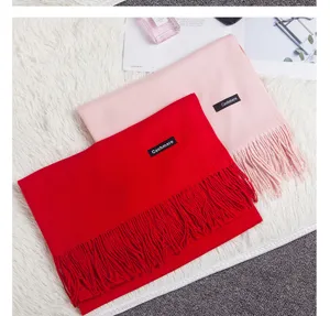 Detail of pink and red cashmere scarves with elegant tassels on white fur