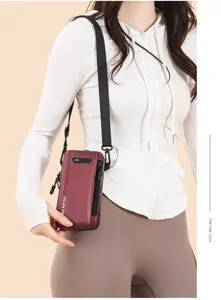 Model carrying a compact maroon vertical crossbody phone bag over a white hoodie