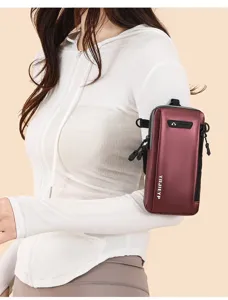 Detailed view of a burgundy sports arm bag with headphone port worn on person's arm