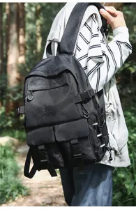 Uomo con un grande zaino nero multitasche in un ambiente forestale.