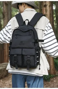 Vista posteriore di un grande zaino da studente nero con tasche multiple nel bosco.