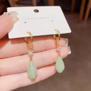 Détail de boucles d'oreilles magnolia style français avec finition dorée et pendentif vert