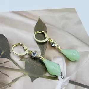 Détail de boucles d'oreilles magnolia de style français avec pierre vert clair.