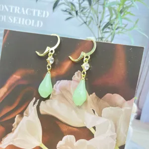 Vue détaillée d'élégantes boucles d'oreilles magnolia vert en forme de goutte d'eau.