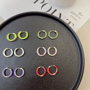 Colorful enamel geometric hoop earrings arranged on a textured black display tray