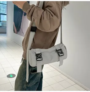 Detailed view of a stylish grey cylinder crossbody bag with grid texture and buckles