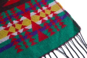 Detailansicht eines Ethno-Strickponchos mit geometrischen Mustern und schwarzen Quasten
