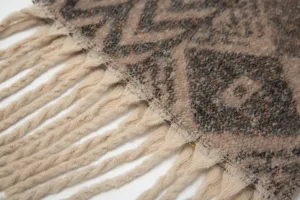 Κοντινό πλάνο χειμερινού κασκόλ ζακάρ με ρόμβους και χοντρές μπεζ φούντες υφή