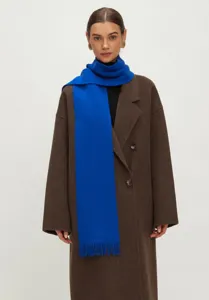 Detailopname van een levendige kleinblauwe gebreide sjaal met franjes over een bruine jas