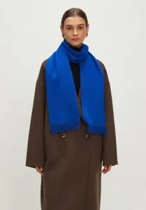 Detailopname van een levendige Klein blauwe gebreide sjaal met elegante franjes op een model.