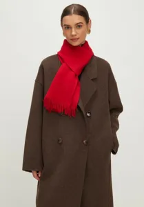 Model met een gezellige rode gebreide sjaal met franjes en een bruine wollen winterjas