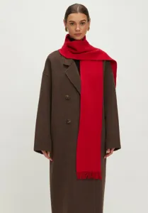 Detailoverzicht van een warme rode gebreide sjaal met elegante franjes over een bruine jas