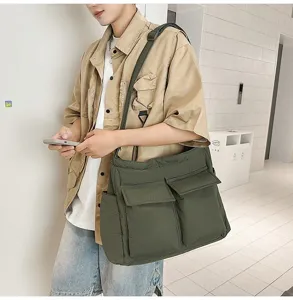 Large casual army green canvas messenger bag for men shown in a minimalist setting