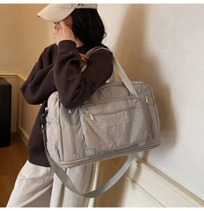 Large grey nylon travel bag with adjustable crossbody strap and front pocket detail
