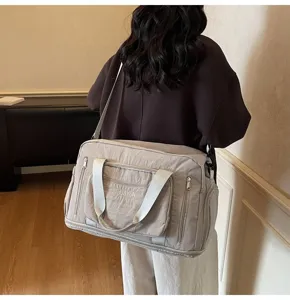 Rear view of a model carrying a beige large capacity travel bag in a home setting